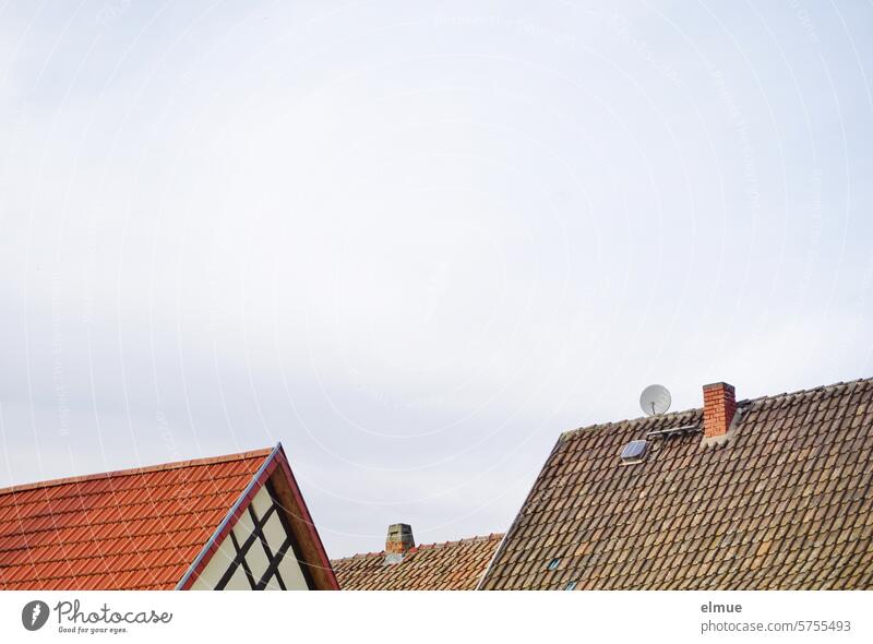 Ziegeldächer mit Schornsteinen, einer Satellitenschüssel, einem Dachfenster und einem Fachwerkgiebel Ziegeldach Giebel Dorf wohnen Dachziegel Blog Fenster