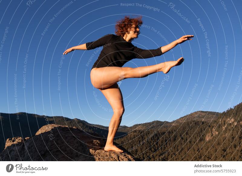 Anmutige zeitgenössische Tänzerin balanciert auf einem Felsen Zeitgenosse Gleichgewicht Frau Blauer Himmel Wald Berge u. Gebirge darstellende Kunst Natur