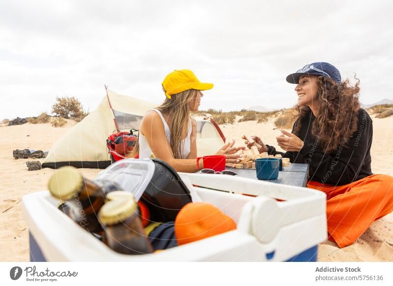 Ein glückliches Paar spielt eine Partie Jenga in seinem Strandcamp und teilt dabei Lächeln und Erinnerungen Camping Spiel Zelt Freizeit Urlaub Frauen
