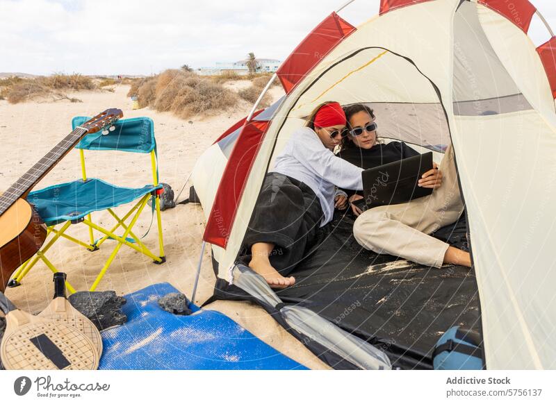 Ein Paar entspannt sich in seinem Zelt mit einem digitalen Tablet und verbindet so auf angenehme Weise Technologie mit seinem Camping-Erlebnis am Strand