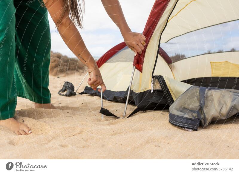 Nahaufnahme einer anonymen Frau, die an einem Strand ein Zelt aufbaut und damit die Essenz von Outdoor-Abenteuer und Teamwork einfängt Camping Einrichtung