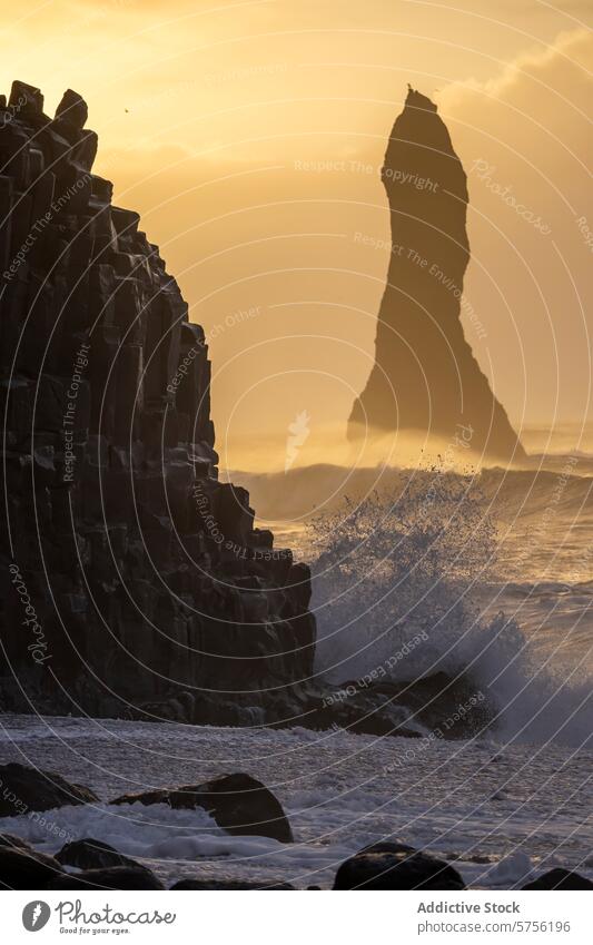 Majestätische Meereslandschaft in Island mit hoch aufragendem Meeresstapel Seeschornstein Sonnenuntergang goldene Stunde Wellen Basaltsäulen Silhouette