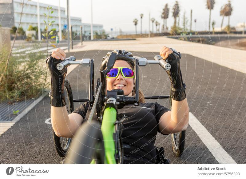 Paralympische Athletin trainiert auf dem Handbike paralympisch Training Frau Tatkraft Sport Lächeln lernfähig Gerät Rollstuhl heiter Rennen Fitness im Freien