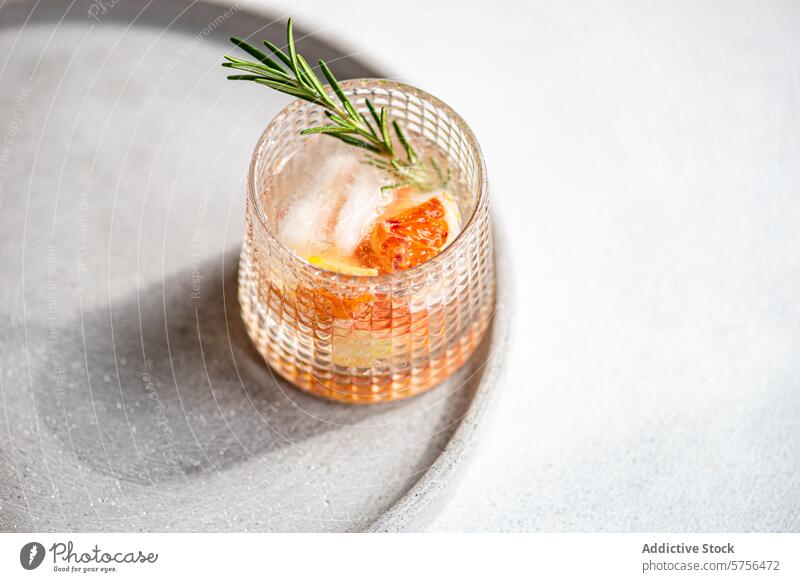 Ein handwerklich hergestellter Wodka-Tonic-Cocktail mit Grapefruit und Rosmarin, der auf einem strukturierten Tablett für ein gehobenes Serviererlebnis ruht