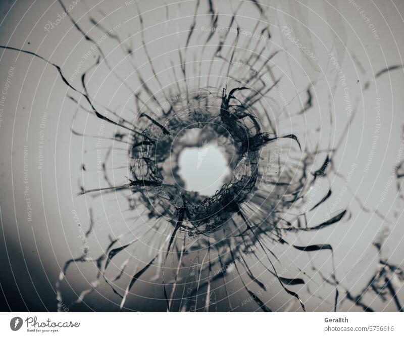 Einschussloch in gesprungenem Fensterglas abstrakt Unfall Hintergrund gebrochen zerbrochenes Glas kaputtes Fenster Gewehrkugel Einschusstreffer Einschussstelle