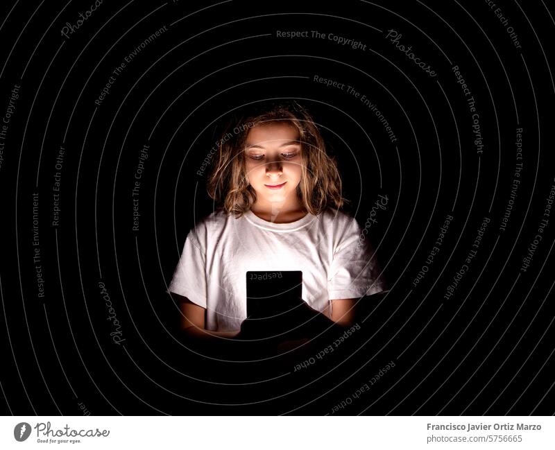 Junges Mädchen in Smartphone vertieft, in der Dunkelheit beleuchtet jung Internet sozial Medien Gefahr online Kind Bildschirm Zeit Nacht Licht Gesicht Hände