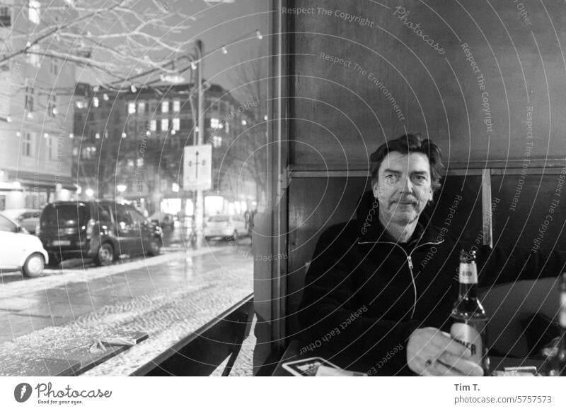 Mann mit Flaschenbier am Fenster einer Bar s/w Schwarzweißfoto Nacht Prenzlauer Berg Berlin Stadt Stadtzentrum Hauptstadt Altstadt bnw Innenaufnahme Café Winter