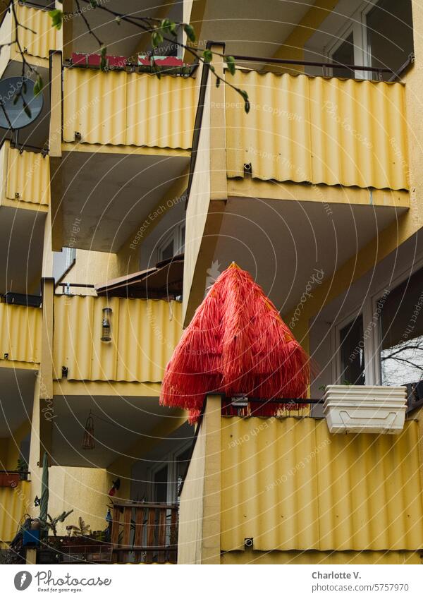 Roter Sonnenschirm auf einem von vielen gelben Balkonen Schirm sonnenschirm roter Schirm hausfassade geschlossener Sonnenschirm urban Haus Gebäude Blumenkästen