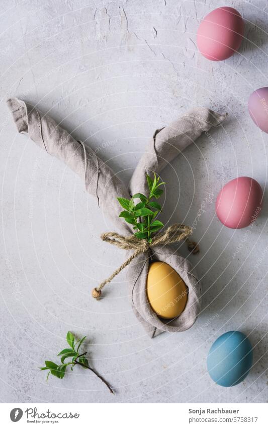 Ein gelbes Osterei mit Hasenohren aus einer Serviette. Draufsicht. Ostern Osterhase Frühling Feste & Feiern Tradition Dekoration & Verzierung