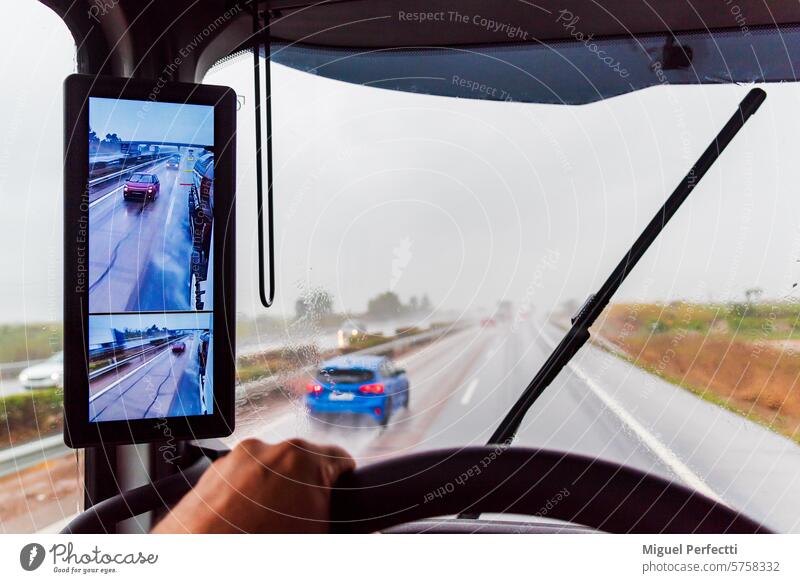 Blick vom Fahrersitz eines Lastwagens auf einer Autobahn mit schlechter Sicht aufgrund von starkem Regen, wobei die Scheibenwischer in Betrieb sind. im Inneren
