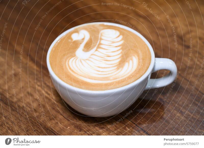 Kunstvolles Lattenschwan-Design auf Holztisch Schwan Kaffee Espresso Cappuccino Barista Café Kultur melken schäumen cremig Textur Tasse weiß hölzern Tisch