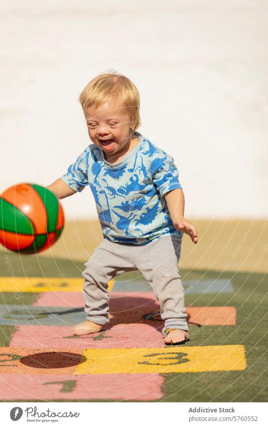 Kleinkind mit Down-Syndrom genießt Spielzeit mit Ball Spielplatz Freude Kind Fröhlichkeit Unschuld sonnig im Freien tagsüber spielen Aktivität Spaß jung
