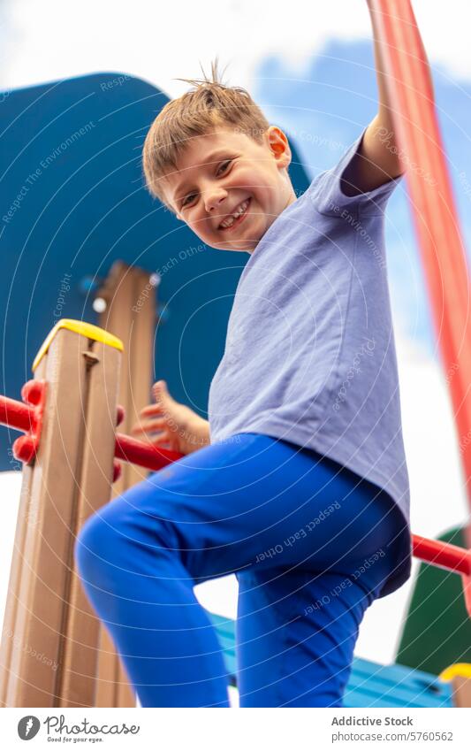Fröhlicher Junge spielt auf einem Spielplatz spielen freudig Klettern Gerät farbenfroh Lächeln Fröhlichkeit im Freien Aktivität Kind jung heiter Erholung