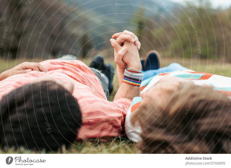 Ein homosexuelles Paar, das Seite an Seite im Gras liegt, findet Ruhe in der Natur, die Hände in einem zärtlichen Zeichen der Liebe und Einheit verschränkt