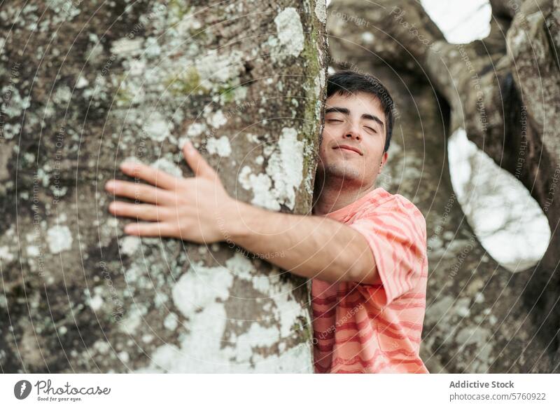 Ein lächelnder Mann umarmt freudig einen großen, mit Flechten bedeckten Baum und zeigt damit seine Verbundenheit mit der Natur, die ihn umgibt. Umarmung Lächeln