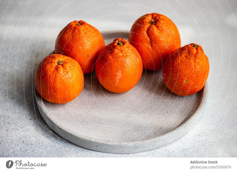 Frische Clementinen auf einem Betonteller Zitrusfrüchte Frucht reif orange Teller rund Nahaufnahme frisch Ordnung grauer Hintergrund saftig Gesundheit Snack