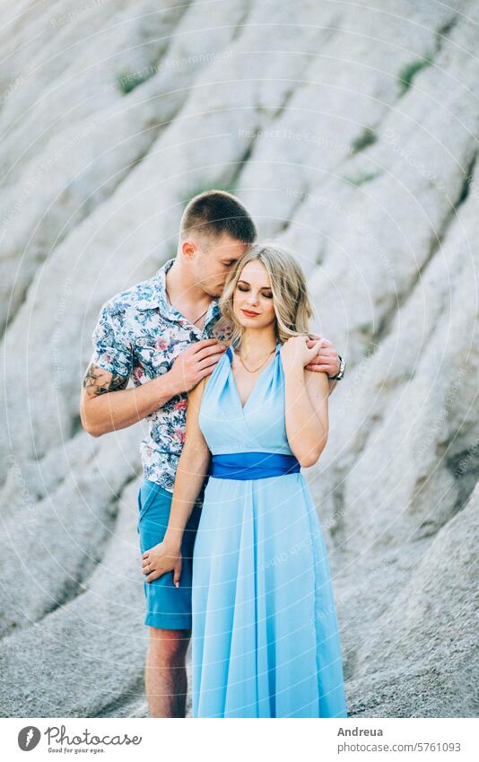 blondes Mädchen im hellblauen Kleid und ein Typ im hellen Hemd in einem Granitsteinbruch Freund jung Teenager für einen Spaziergang Zusammensein Steinbruch Kies
