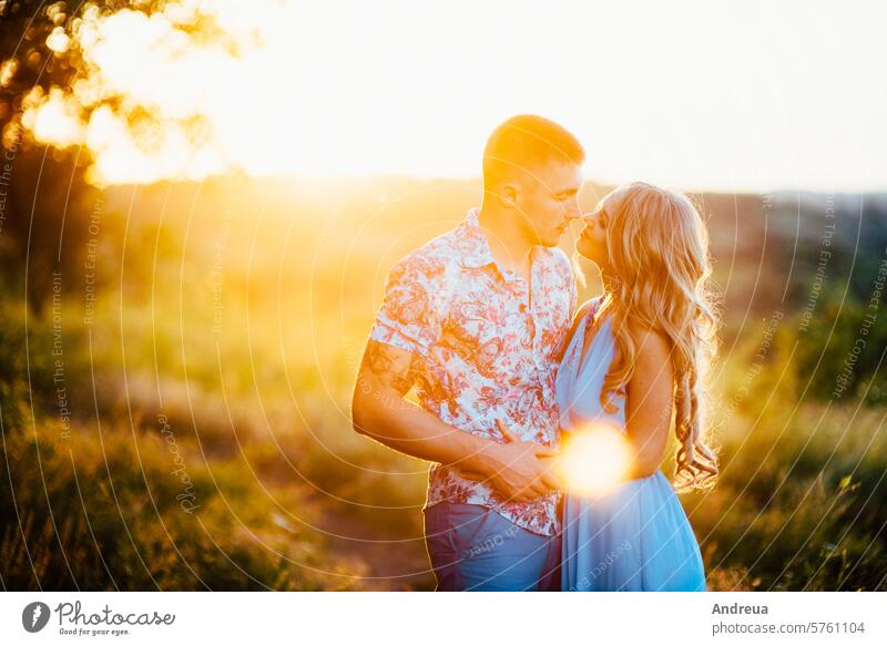 blonde Mädchen mit losen Haaren in einem hellblauen Kleid und ein Kerl im Licht des Sonnenuntergangs Air Schönheit Freund Braut Tag Engagement Abend Familie