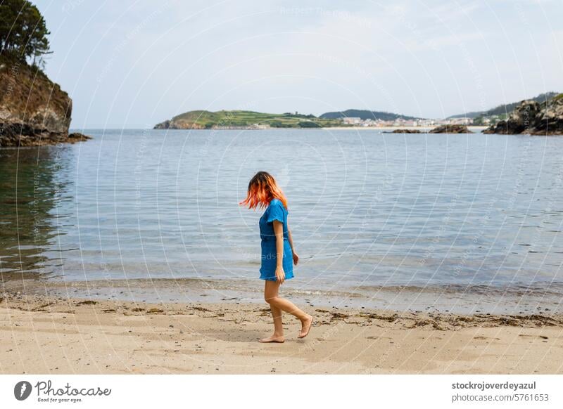 Ein junges Mädchen mit orangefarbenen Haaren spaziert ruhig an einem Naturstrand in Nordgalicien entlang Meer Strand Frau Sommer MEER laufen desclza Ufer