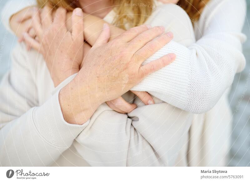 Nette Frau umarmt zärtlich ihre reife Mutter am Muttertag. Nahaufnahme der Hände. Mama Erwachsener Kind Umarmen Tochter Eltern Freunde außerhalb Gesundheit