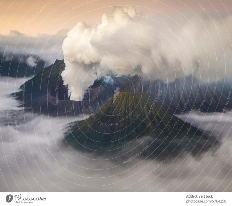 Ein atemberaubender Blick auf den Rauch des Vulkanausbruchs, der in der Morgendämmerung über den nebelverhangenen Bergen aufsteigt, und das sanfte Licht, das die Szene umschmeichelt