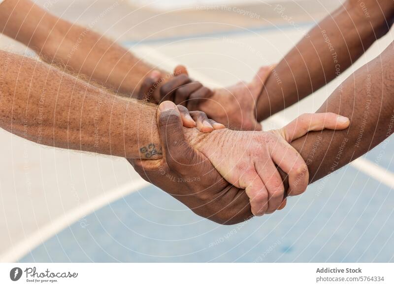 Nahaufnahme von multiethnischen Basketballspielern, die sich im Kreis an den Händen fassen und damit ein starkes Symbol für das Engagement und das Vertrauen eines Teams darstellen