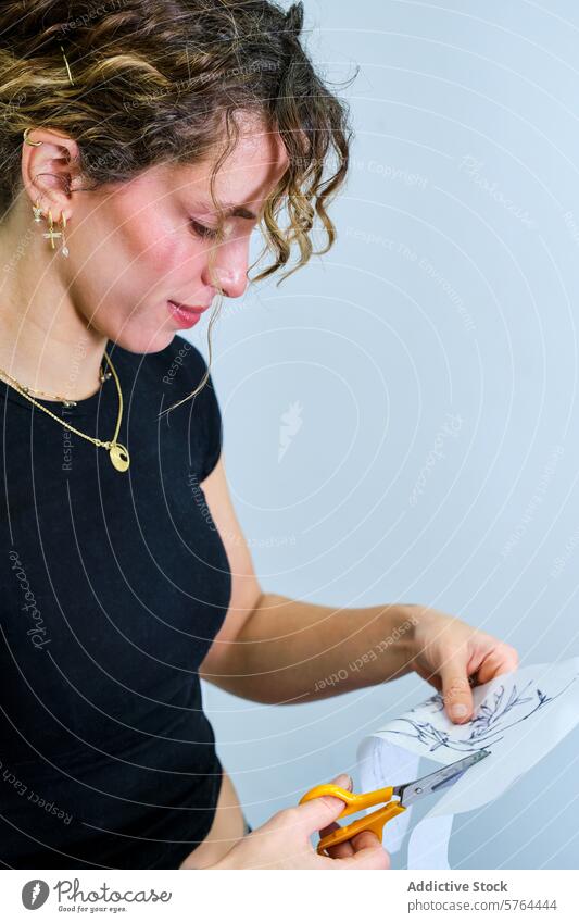 Frau schneidet sorgfältig Papiermuster im Atelier aus Schneiden Schere Design Fokus krause Haare Basteln Kunst Künstler Kreativität Präzision Konzentration