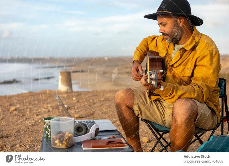 Nomadischer Musiker komponiert mit Laptop am Meer bei Sonnenuntergang Gitarre Mann MEER nomadisierend Wohnmobil Inspiration Seeküste Melodien Composing