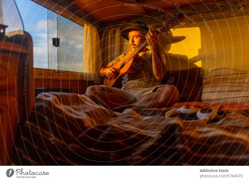 Nomadenmusiker komponiert bei Sonnenuntergang im Wohnmobil Musiker Mann Gitarre MEER Inspiration nomadisierend Composing gemütlich Licht warm Innenbereich