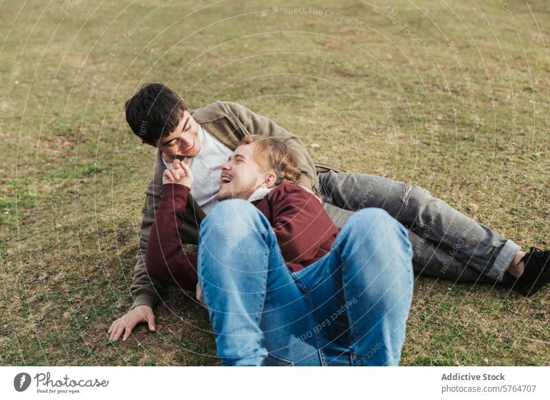 Ein unbeschwerter Moment entfaltet sich, als ein Mann im Gras liegt und mit seiner Partnerin im Freien lacht und spielerisch interagiert. lachen Feld