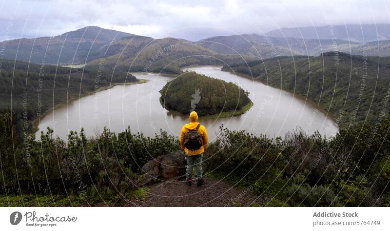 Anonymer Wanderer mit Blick auf eine malerische Flussschleife im Winter Irrfahrt übersehen Hügel grün Mann Landschaft Natur im Freien Reise Abenteuer Einsamkeit