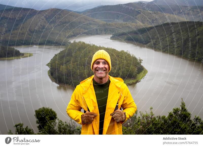 Mann in gelber Jacke genießt die Aussicht auf den Fluss im Winter Beanie Lächeln Landschaft Abenteuer im Freien malerisch reisen Natur heiter Erwachsener