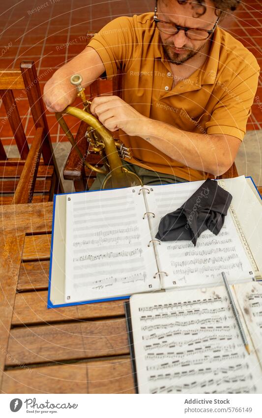 Einarmiger Trompeter übt Musik in seinem Innenhof einarmig Musiker üben Schot Hof männlich Mann Kreativität im Freien Instrument hölzern Stuhl Brille Tatkraft