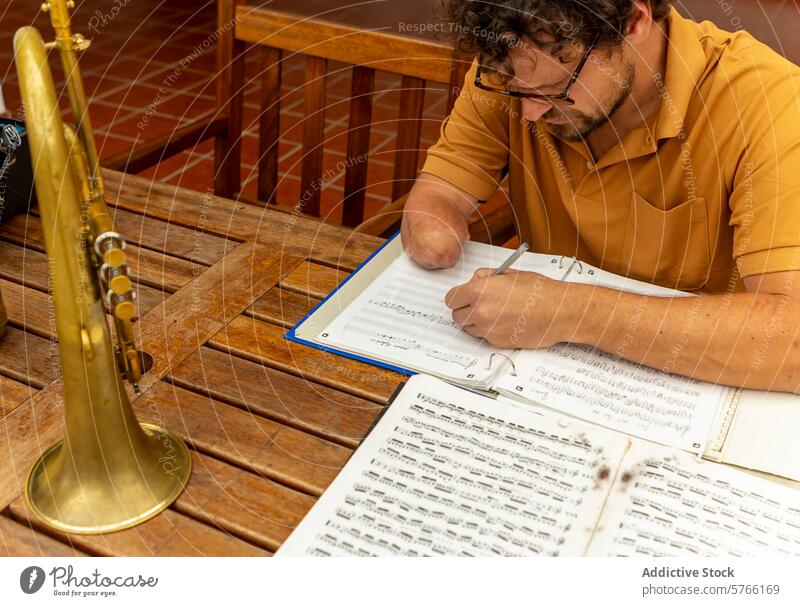 Entschlossener einarmiger Trompeter komponiert Musik zu Hause Komponist schreibend heimwärts Hof Mann männlich kreativ Prozess Tatkraft Schriftsteller Musiker
