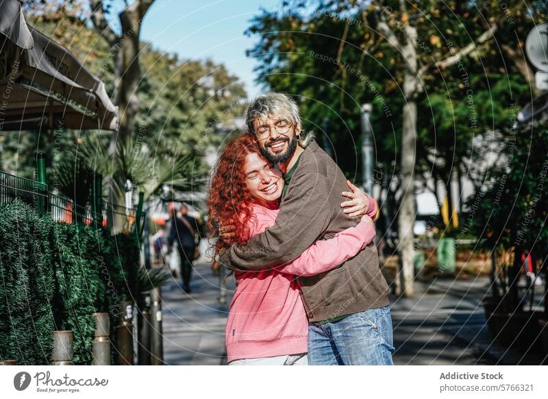 Ein fröhliches Paar umarmt sich auf einem Bürgersteig, umgeben von Grün und der Hektik des städtischen Lebens Umarmung Freude Großstadt urban Glück Umarmen