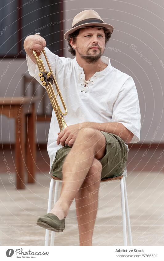 Inspirierender einarmiger Trompeter beim Üben im Freien Mann praktizieren Belastbarkeit Tatkraft Leidenschaft Musik Instrument gold Stuhl Sitzen Sommer Hut