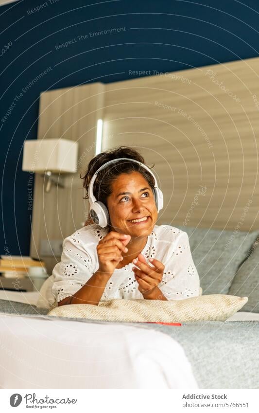 Fröhliche hispanische Frau mittleren Alters, die sich zu Hause bei Musik entspannt Kopfhörer mittleres Alter hören Lächeln reif Erholung heimwärts Liege Glück