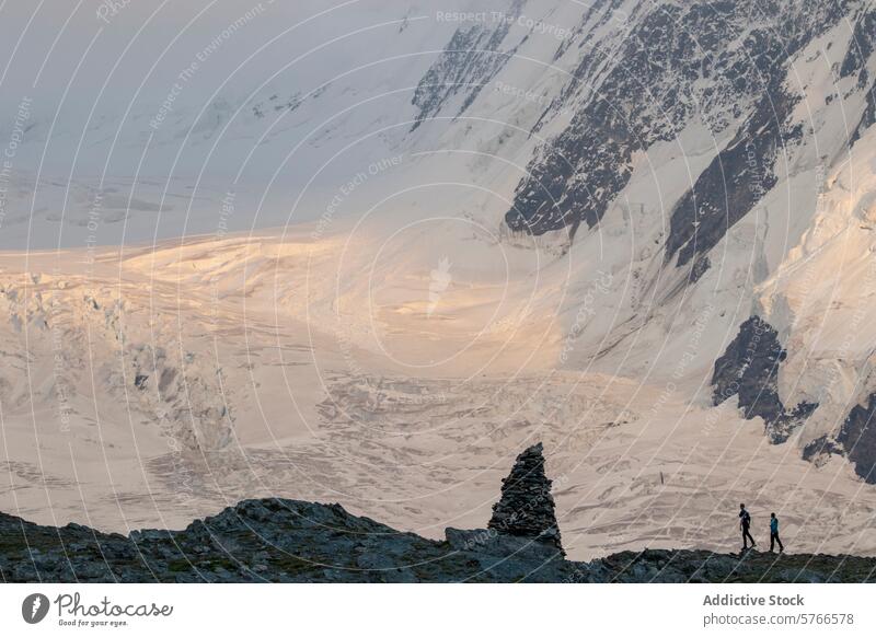 Wanderer überqueren einen Grat mit einem atemberaubenden Blick auf einen Gletscher, der im warmen Licht der untergehenden Sonne in den Schweizer Alpen glänzt