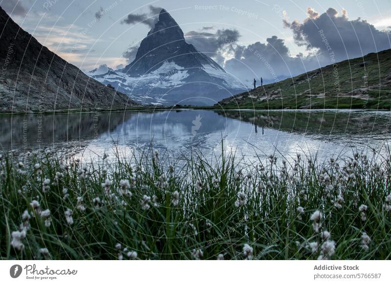 Das majestätische Matterhorn spiegelt sich in der Abenddämmerung im stillen Wasser eines Bergsees, und die Schaulustigen in der Ferne verleihen der Szene zusätzliche Größe