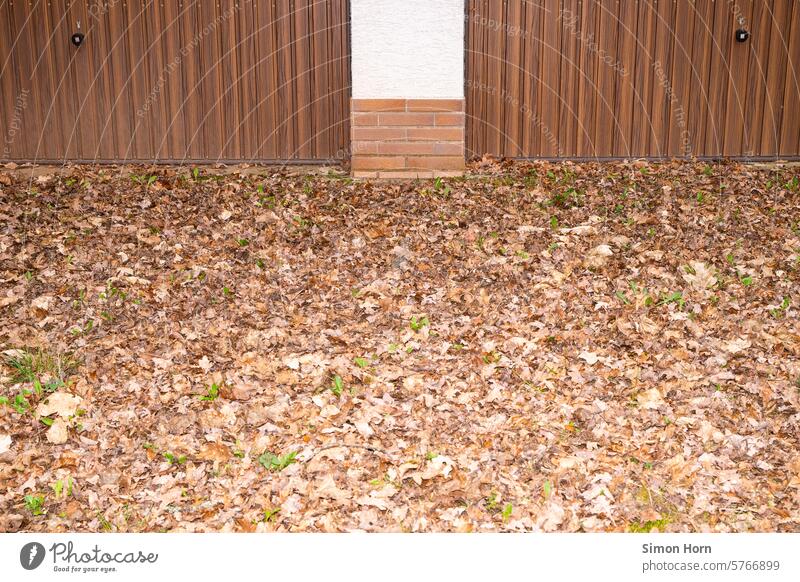 der Boden vor einer Doppelgarage ist von einer dicken Schicht trockenen Laubes bedeckt Brauntöne Einfahrt Blätter Garage Garagentor geschlossen trist Bodenbelag