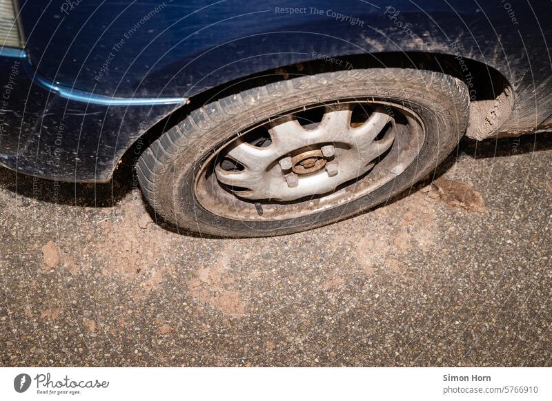 alter, verschmutzter Reifen eines Autos verliert trockene Erde, der umgebende Asphalt ist dreckig und staubig Autoreifen Fortbewegungsmittel Feldweg Trockenheit