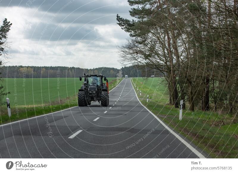 Traktor auf zweispuriger Landstraße Frühling Farbfoto Landwirtschaft Landschaft Feld Außenaufnahme Ackerbau Tag Maschine