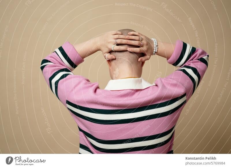 Minimale Rückenansicht einer kahlen jungen Frau mit Händen auf dem Kopf, Alopezie und Krebsüberlebenskonzept Mädchen gen z Haarausfall Chemotherapie Rückansicht