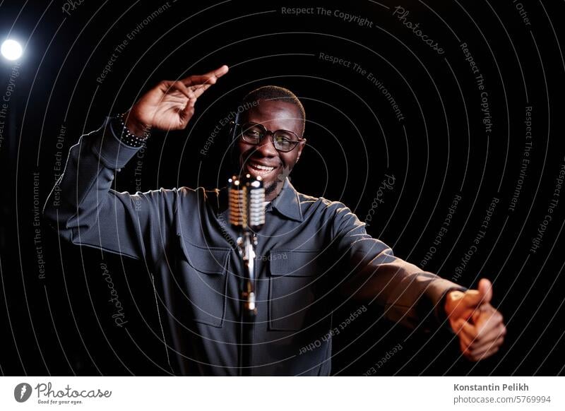 Minimal Taille bis Porträt der emotionalen afroamerikanischen Mann spricht zu Mikrofon und Durchführung auf der Bühne mit Spotlight Kopie Raum aufstehen Komödie