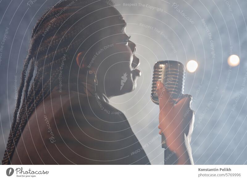 Seitenansicht Porträt der afroamerikanischen Frau singt zum Mikrofon auf der Bühne mit Rauch im Hintergrund Kopie Raum singen Gesang Konzert Live Musik Künstler