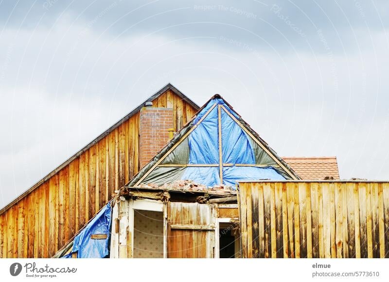 Hausgiebel mit Holzverkleidung, teilweise abgerissen und mit einer Plane versehen Abrissgebäude Giebel Abdeckplane wohnen Dachgiebel Schornstein Dachziegel