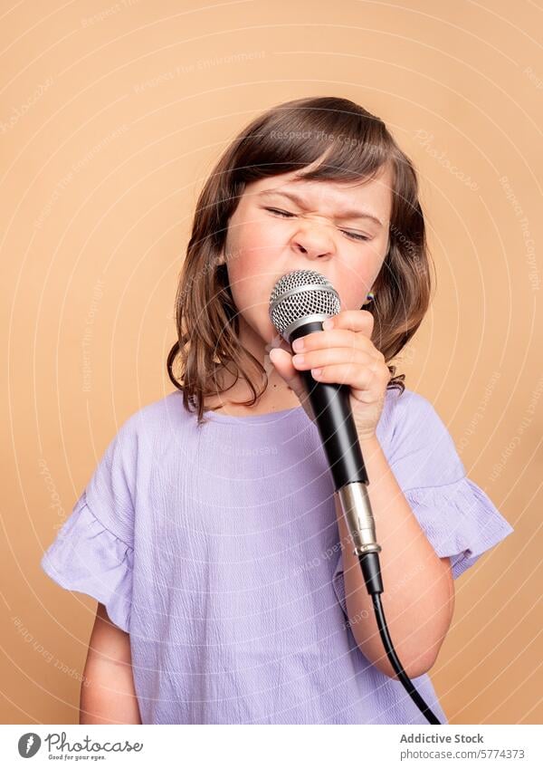 Junges Mädchen singt leidenschaftlich in ein Mikrofon jung Gesang beiger Hintergrund lila Hemd Kind Leistung Musik Talent Grimasse Ausdruck Sängerin Hobby