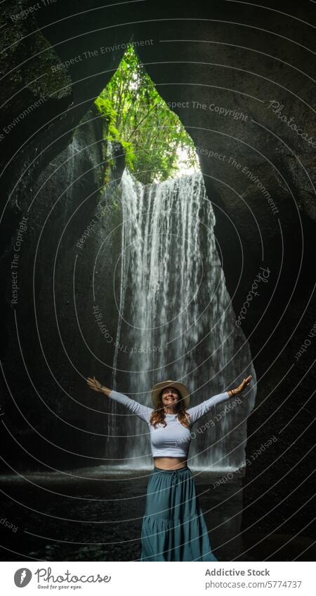 Fröhliche Frau, die die Natur am Bali-Wasserfall umarmt Indonesien reisen Tourismus Freude Arme ausgestreckt Hut grün Gelassenheit üppig (Wuchs) abgelegen