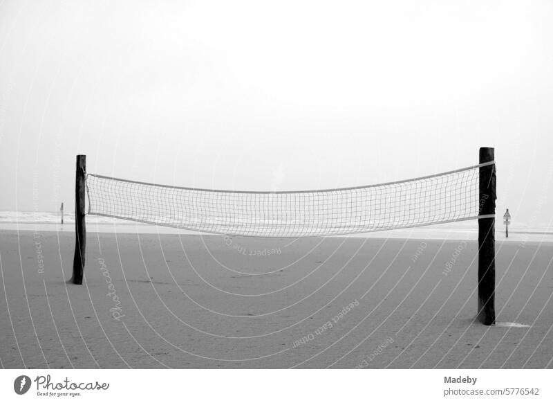 Volleyball Netz für Beach Volleyball bei Regen und Sturm am Strandspielplatz am Strand von St. Peter-Ording im Kreis Nordfriesland in Schleswig-Holstein im Herbst an der Nordseeküste in neorealistischem Schwarzweiß
