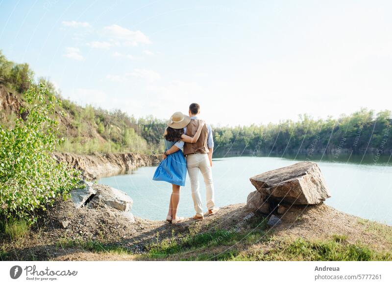 Ein junges Paar, ein Mann und ein Mädchen, gehen in der Nähe eines Bergsees spazieren. Kleid blau Spaziergang Steine Berge u. Gebirge See Frühling Sommer Liebe